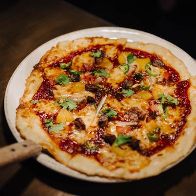 Pizza with BBQ sauce, short ribs, bacon, cheese, and jalapenos.