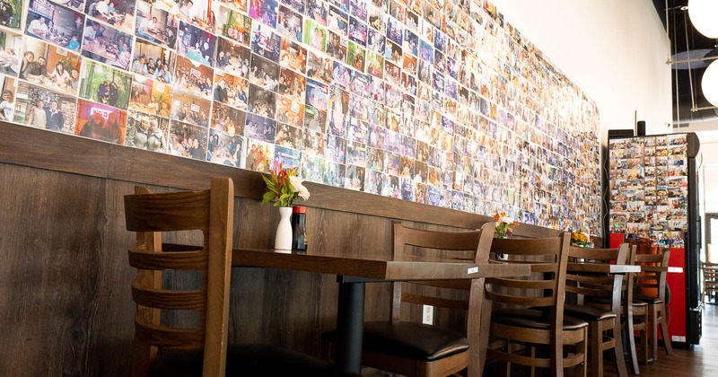 Interior, tables and chairs near wall with photos