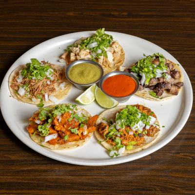 Tacos with assorted meats, onions, cilantro, lime, and red and green salsas.