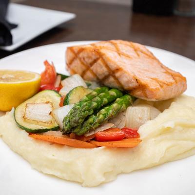 Grilled salmon served with mashed potatoes and grilled veggies.