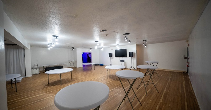 Interior, event space, round white tables, TV with sound system, wooden flooring