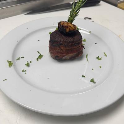 Filet Minon wrapped in bacon garnished with rosemary spring.