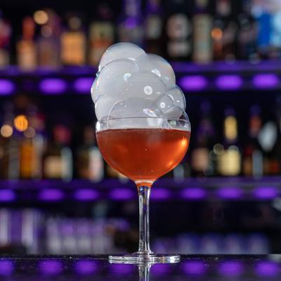 Cocktail in coupette glass with smoke bubbles on top.