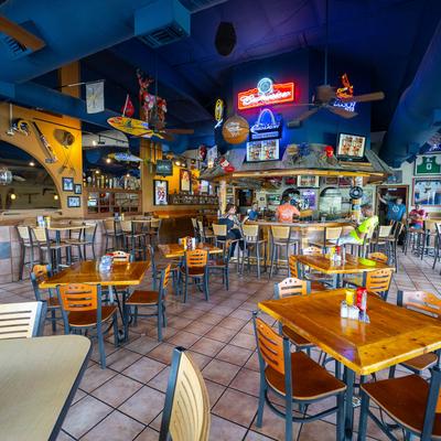 Interior with neon signs, wooden tables, and a bar.