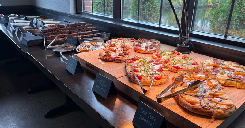 A buffet table featuring various food items, including several flatbreads or pizzas