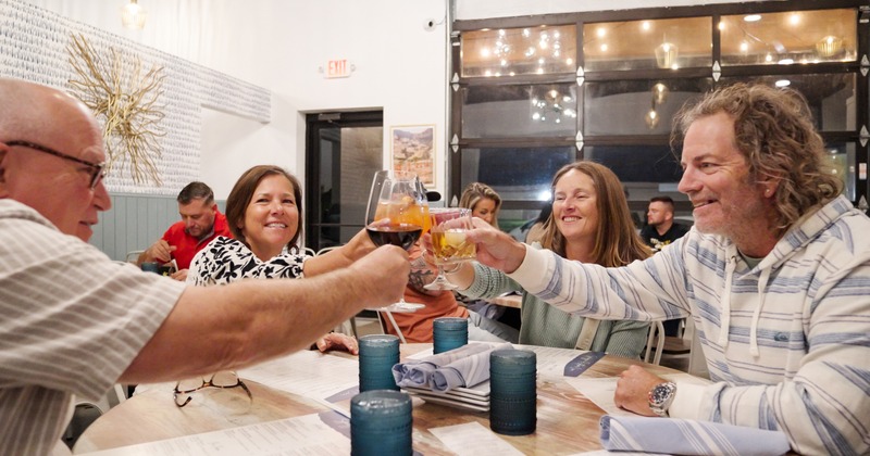 Four guests sitting at a restaurant table and make a toast