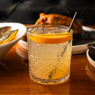 Gin and tonic served in a rocks glass with orange slice garnish.
