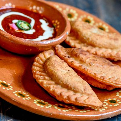 Empanadas served with red sauce.