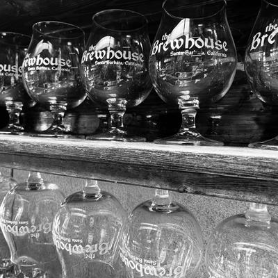 Cleaned Tulip beer glasses on shelf and also hanging upside down with The Brewhouse printed on them.