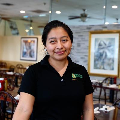 Staff member posing in a restaurant setting.