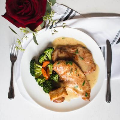 Chicken in creamy sauce served with broccoli and carrots.