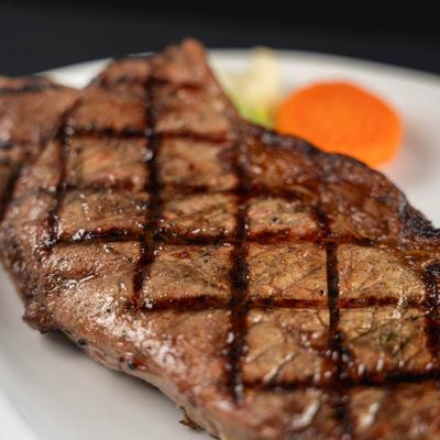 A close-up of a New York steak with crosshatch marks, served with steamed veggies.