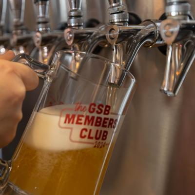 Draft beer pouring into a branded glass mug from the tap.