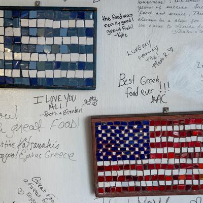 Wall detail, Greek and the US mosaic flags with writings left by customers