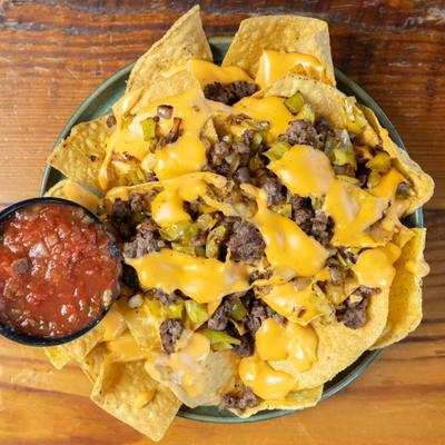 Nachos with melted cheese and beef served with salsa.