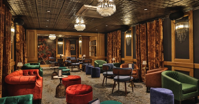 Luxurious lounge with velvet seating, chandeliers and warm drapery.