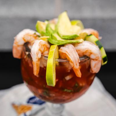 Shrimp cocktail featuring chilled shrimp and avocado slices served in a goblet.