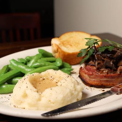 Bacon wrapped filet mignon with mash potatoes , snap peas and toasted french bread.