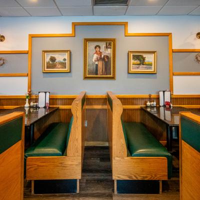 Restaurant booth seating with framed paintings on the wall above.