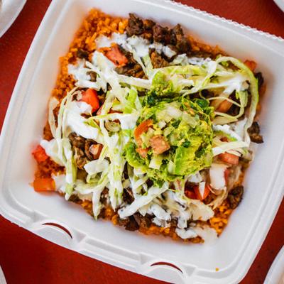 Rice Bowl featuring carne asada, shredded lettuce, pico de gallo, and guacamole.