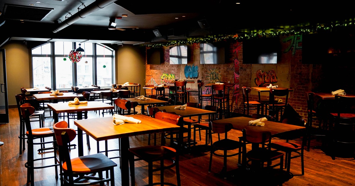 Interior of a restaurant with wooden tables and exposed brick walls with graffiti