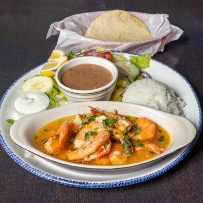 Shrimp in garlic sauce served with rice, beans, sour cream, salad and tortillas.