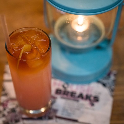 Craft cocktail in a tall glass with a candle lantern in the background.