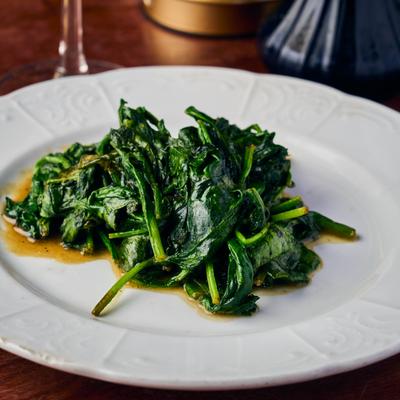 Sauteed spinach drizzled with olive oil on a white plate.