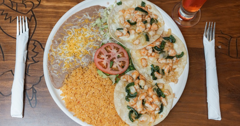 Shrimp tacos served with rice and refried beans