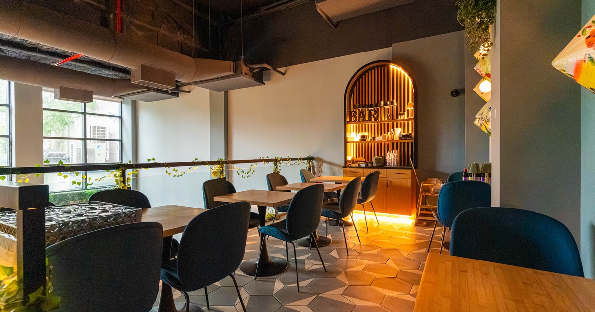Interior seating area with circular tables and chairs, and an arched wooden bar area