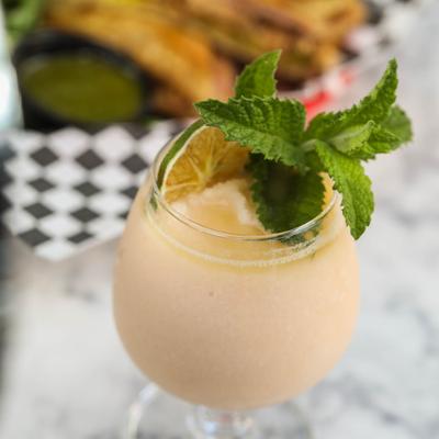 Light pink cocktail drink garnished with mint leaves and lime.