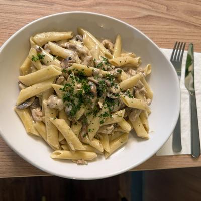 A serving of penne pasta with a creamy mushroom sauce.