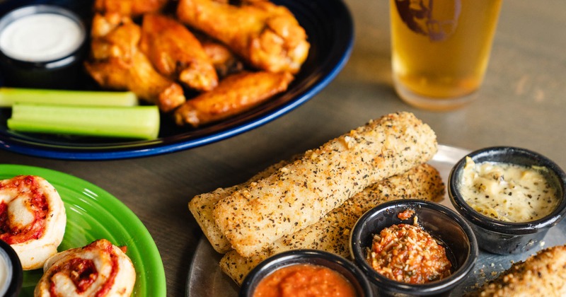 Multiple food plates and a beer