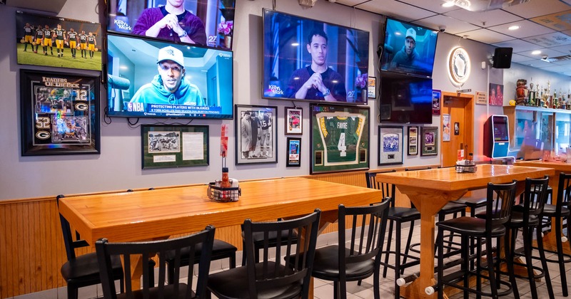 Interior, high top tables and chairs, TV screens on the wall