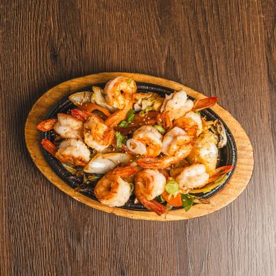 BBQ Shrimp served in a skillet on a wooden base.