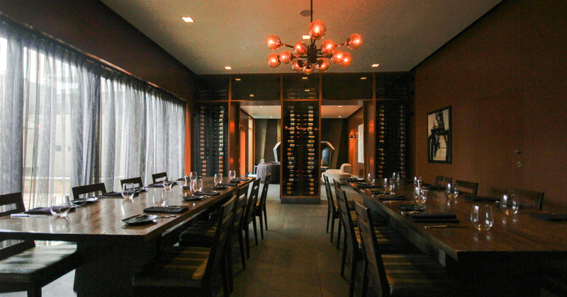 Interior, two long tables with wine glasses, wine racks