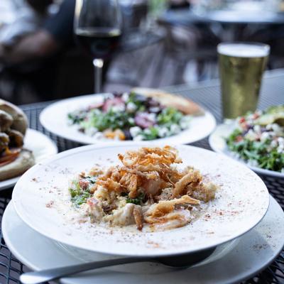Coastal Shrimp & Grits  with other dishes and drinks on a table outside.