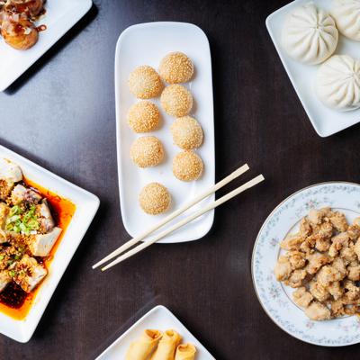 Asian food assortment with sesame balls, steamed buns, and spring rolls.