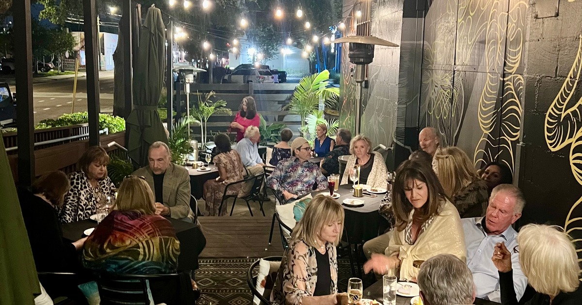 A flautist and a guitarist playing outdoors surrounded by greenery