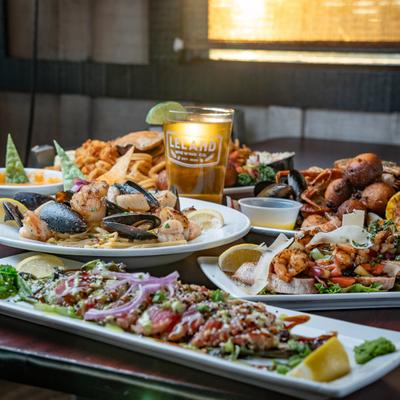 Seafood platter with assorted plates spread on a table with a glass of beer.