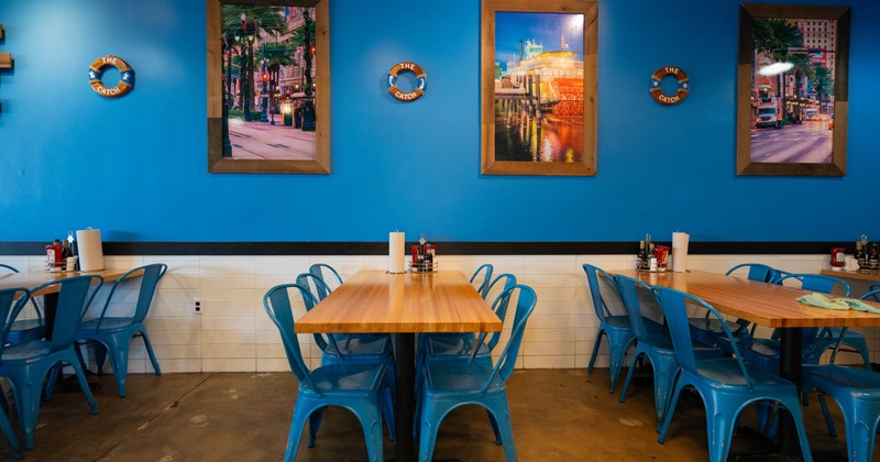 Interior with blue walls, wooden tables and blue metal chairs, with nautical-themed decor