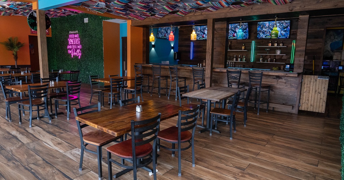 Cozy interior dining area with wooden tables and chairs, and a bar with TV sets