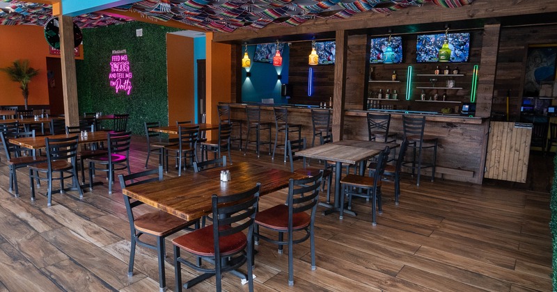 Cozy interior dining area with wooden tables and chairs, and a bar with TV sets