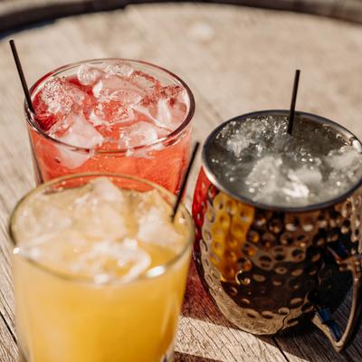 Three cocktails on a wooden barrel.