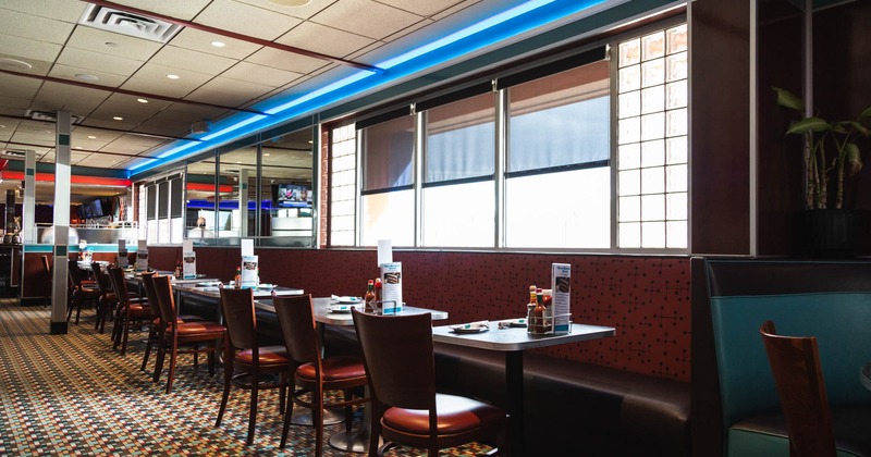 Interior, lined up tables  and chairs with a long wall bench seating