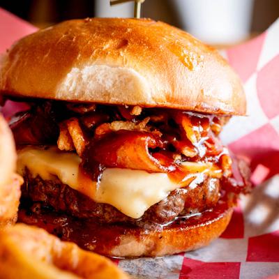Close-up of a bacon cheeseburger with melted cheese and barbecue sauce.