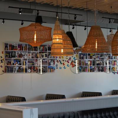 Interior, booths, large woven pendant lights, bookshelves and butterfly decals on a wall.