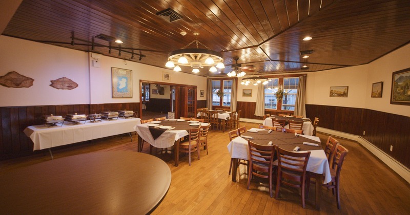 Interior, dining room, wooden tables and chairs, white tablecloths, and decorative light fixtures