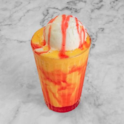 Mango shake topped with a scoop of ice cream and drizzled with fruit syrup.