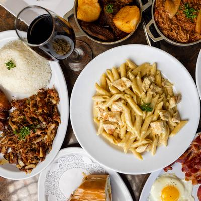 A spread of assorted dishes served with a glass of red wine, overhead view.